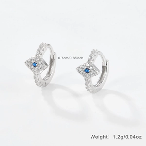 Macro shot of silver evil eye huggie earrings with blue gemstones and diamonds