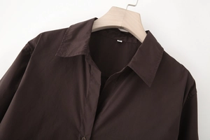 Detail of the V-neck lapel and woven fabric on a dark brown long-sleeved poplin shirt