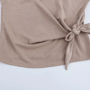 Detailed close-up of soft brown knit fabric featuring a side tie-up bow design and texture