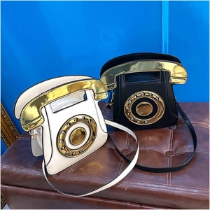 Close-up of retro rotary phone shaped shoulder bags in black and white sequin PU leather
