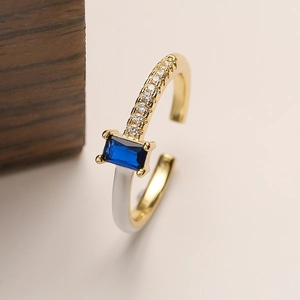 Detail of 18K gold plated copper ring featuring blue gemstone and white enamel finish
