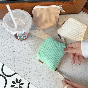 Détail de mini pochettes en maille gaufrée menthe, crème et kaki avec fermetures zippées