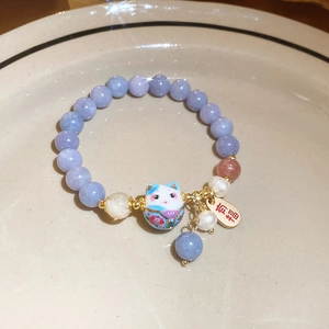 Dettaglio del bracciale con perline, pendente gatto della fortuna e ciondolo Fu