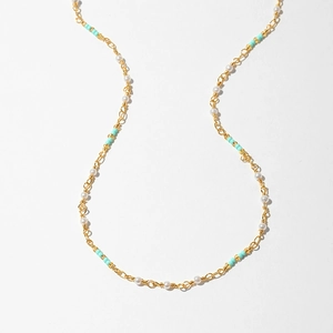 Close-up of bohemian gold chain necklace with turquoise beads and evil eye detail