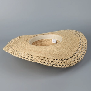 Detail of wide brim straw sun hat featuring hollow crochet edge and interior sweatband