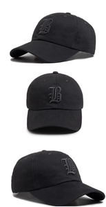 Detail view of gothic letter B embroidery on black cotton baseball cap with twill texture