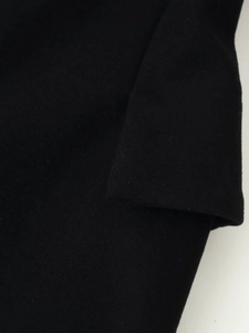 Close-up of the black wool fabric texture and stitching details on a long coat