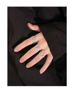 Close-up of minimalist silver heart rings on a hand with black blazer background