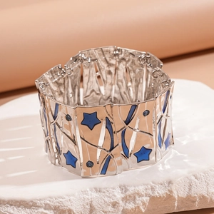 Macro view of wide silver metal bracelet with blue star inlay on white rock