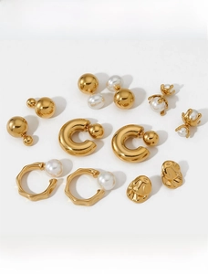 Flat lay of diverse gold plated pearl earrings including hoops and studs on white background