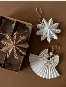 Artistic detail of kraft paper snowflake and angel ornaments in a premium gift box