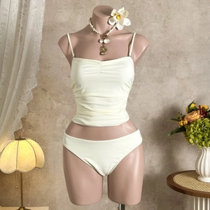 Close-up of ruched solid bikini set in pale yellow with a delicate shell necklace detail