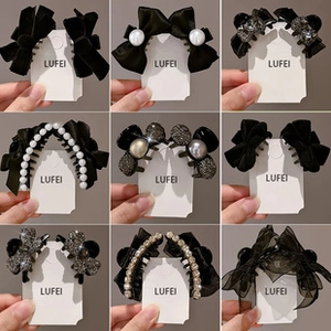 Macro view of assorted black hair clips with velvet, rhinestones and pearls on cards