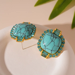 Vue macro de boucles d'oreilles vintage en or avec turquoise et strass bleu clair