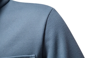 Detailed macro view of gray-blue waffle knit fabric texture and shoulder stitching seam