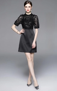 Detail of elegant black dress featuring intricate lace, beads, and sleek satin skirt