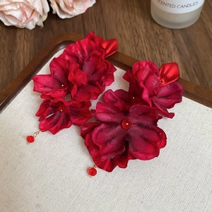 Detail of red fabric flower earrings with pearls on an elegant decorative tray