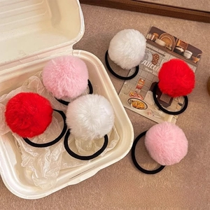 Detail of red, pink, and white faux fur pom pom hair ties with elastic black bands