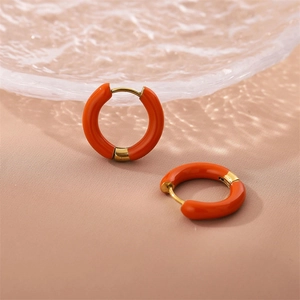 Chic orange enamel gold hoop earrings displayed on a minimalist textured glass tray