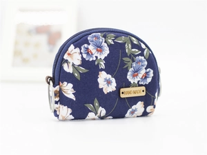 Macro view of blue floral fabric coin purse with hand made wood tag and zipper