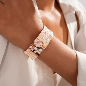 Détail d'un large bracelet doré avec fleurs et papillons en émail rose sur poignet
