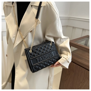 Close-up of black quilted crossbody bag featuring FASHION embossing and metal chain strap