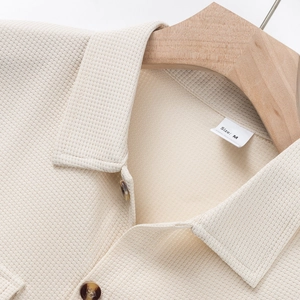 Primer plano de camisa de punto gofre beige con cuello de polo y botones de carey