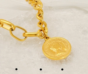 Detailed macro view of a gold-plated queen coin pendant on a chunky steel chain