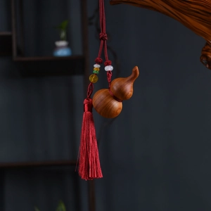 Detailed close-up of a wooden gourd keychain with vibrant red silk tassels and colorful beads