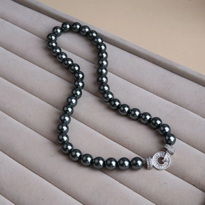 Macro shot of high-luster black pearls with a micro-paved zircon clasp on a velvet tray