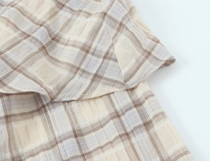 Close-up of beige plaid fabric texture and premium stitched hem detailing on crop top