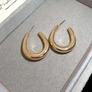 Macro detail of gold U-shaped hoop earrings on gray velvet jewelry display box