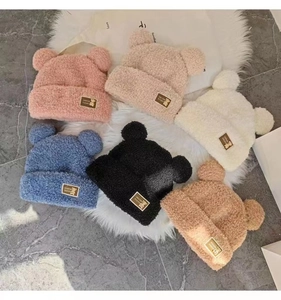 Detailed view of plush knitted bear ear hats in pink, beige, white, blue, and brown