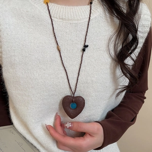 Detail of beaded ethnic necklace with large heart pendant on a white plush sweater