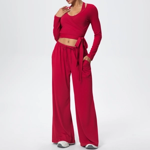 Détail d'un ensemble de yoga rouge avec haut cache-cœur et pantalon large à taille haute