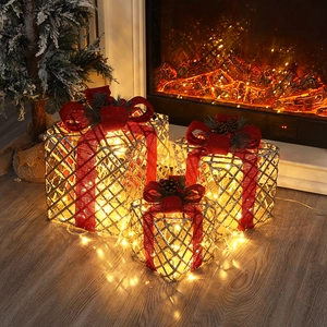 Close-up of three glowing gold wire Christmas gift boxes with red bows and warm LED lights