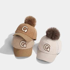 Detail von Kinder-Fleece-Baseballkappen mit Pompon und Stickerei mit dem Buchstaben G