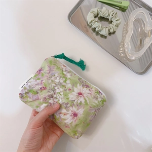 Detail of floral canvas mini pouch with simple wish label and green rope zipper puller