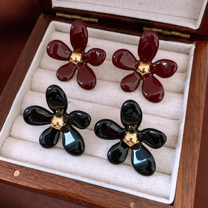 Gros plan de boucles d'oreilles fleurs en acrylique rouge et noir dans un écrin en bois