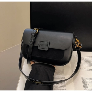 Detail of black matte and suede patchwork shoulder bag with golden hardware