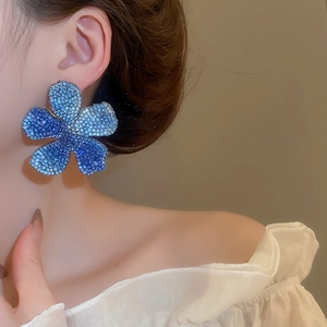 Detail of blue gradient rhinestone flower earrings worn to show large floral design