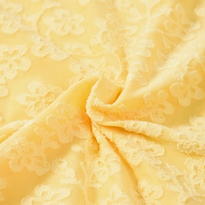Gros plan détaillé du tissu en dentelle florale jaune montrant des motifs jacquard texturés