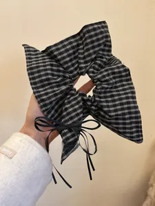 Detail of a large black and white plaid scrunchie with a black ribbon bow accessory