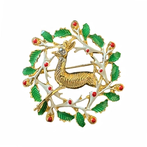 Detail of Christmas reindeer brooch with green enamel leaves and red berries