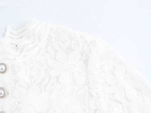Gros plan d'un col en dentelle blanche avec boutons de perles et manches cloches élégantes