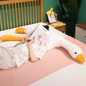 Detail of soft white goose plush pillow on pink blanket with a cozy bedroom background