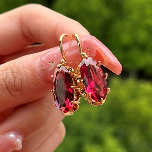 Primer plano de pendientes dorados vintage con grandes gemas ovaladas de color rubí