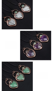 Three heart-shaped gemstone pendants in clear quartz, amethyst, and green aventurine
