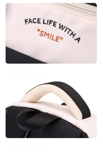 Détail de la poignée rembourrée et de la broderie sur le sac à dos noir et blanc