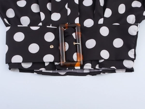 Detail der Taillengürtel mit Schildpatt-Schnalle auf schwarzer Polka-Dot-Bluse